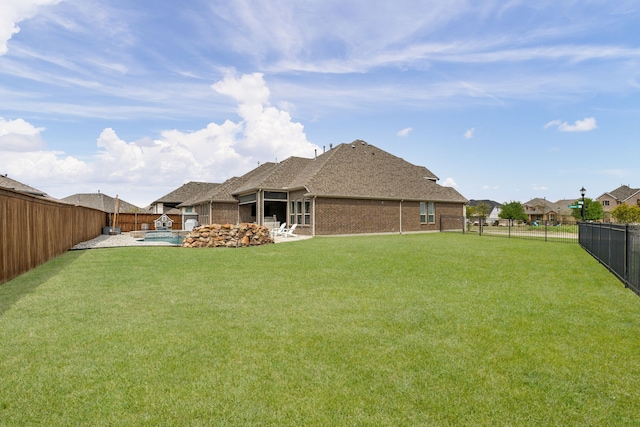 back of house featuring brick siding, a fenced backyard, a yard, and a fenced in pool