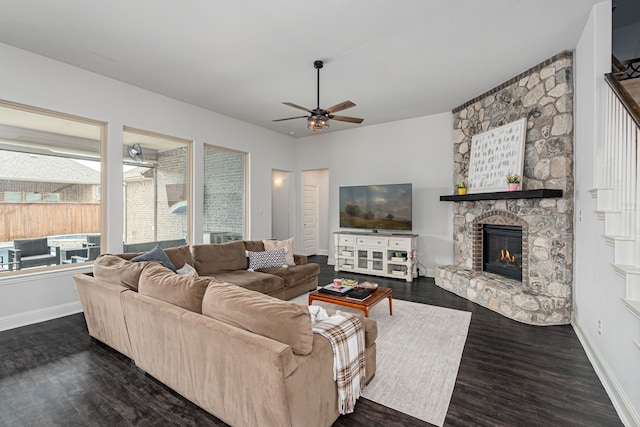 living room with baseboards, a ceiling fan, dark wood-style floors, and a fireplace