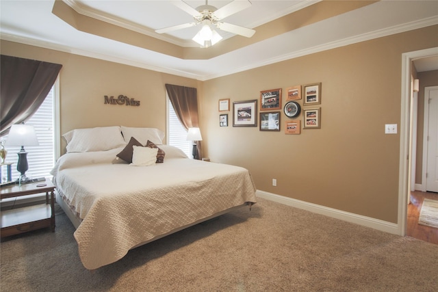 carpeted bedroom with a raised ceiling, crown molding, and baseboards