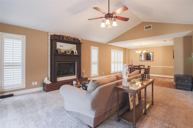 living area with vaulted ceiling, ceiling fan with notable chandelier, baseboards, a large fireplace, and visible vents