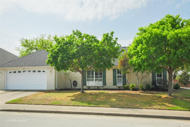 view of property hidden behind natural elements featuring brick siding, concrete driveway, a front lawn, and an attached garage