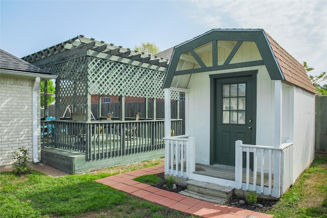 exterior space with brick siding, fence, a gambrel roof, and a pergola
