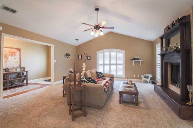 carpeted living area with vaulted ceiling, baseboards, visible vents, a ceiling fan, and a fireplace
