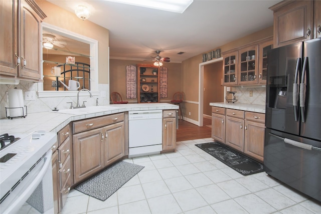 kitchen with a ceiling fan, tile counters, glass insert cabinets, white appliances, and decorative backsplash