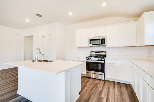 kitchen with stainless steel appliances, a center island with sink, a sink, visible vents, and wood finished floors