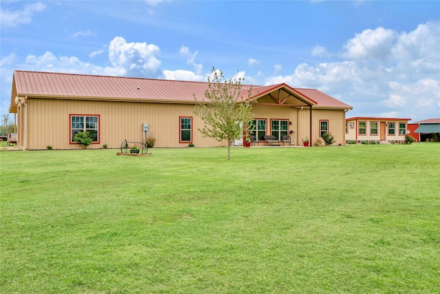 rear view of house featuring metal roof and a yard