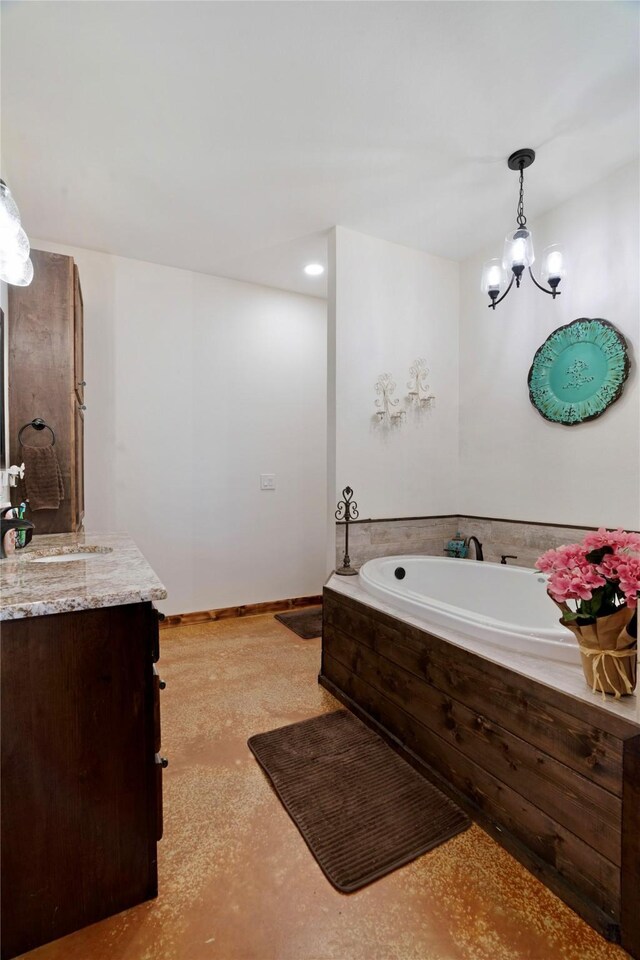 bathroom featuring an inviting chandelier, vanity, baseboards, and a garden tub