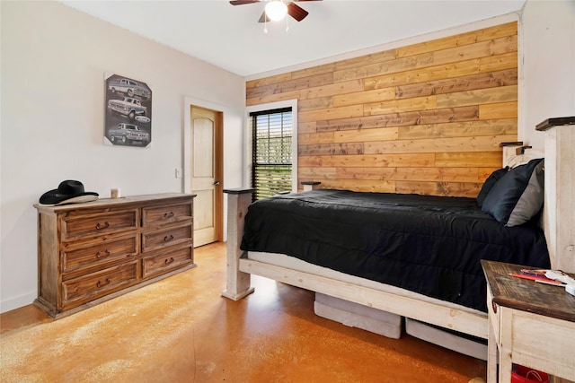 bedroom with finished concrete flooring, ceiling fan, and wooden walls