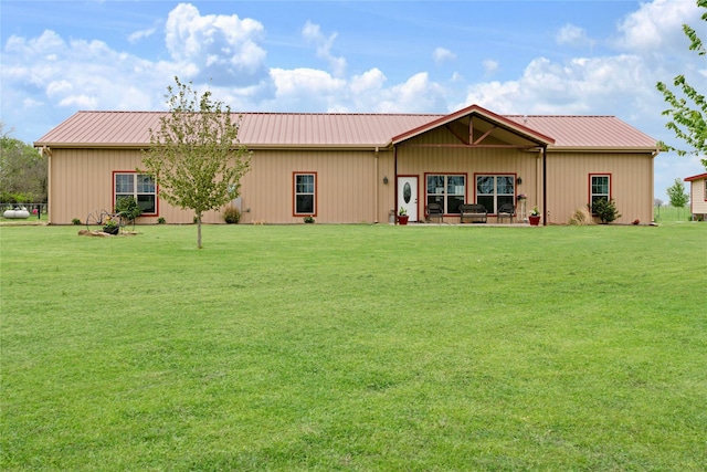 rear view of property featuring a lawn and metal roof
