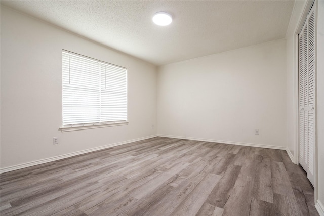 3100 E Park Blvd, Plano, TX 75074 - unfurnished bedroom with a closet, wood finished floors, a textured ceiling, and baseboards