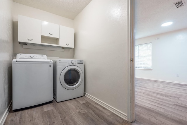 3100 E Park Blvd, Plano, TX 75074 - laundry area featuring washing machine and clothes dryer, light wood-type flooring, cabinet space, baseboards, and a textured ceiling