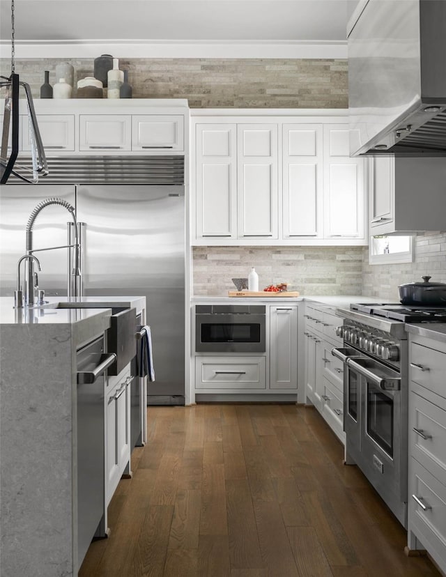 2205 Wheeler Dr, Southlake, TX 76092 - kitchen with appliances with stainless steel finishes, wall chimney exhaust hood, white cabinets, dark wood finished floors, and tasteful backsplash