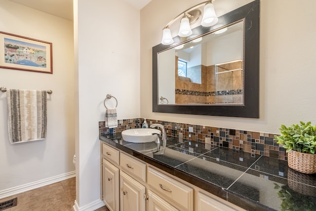 bathroom with toilet, vanity, backsplash, baseboards, and visible vents