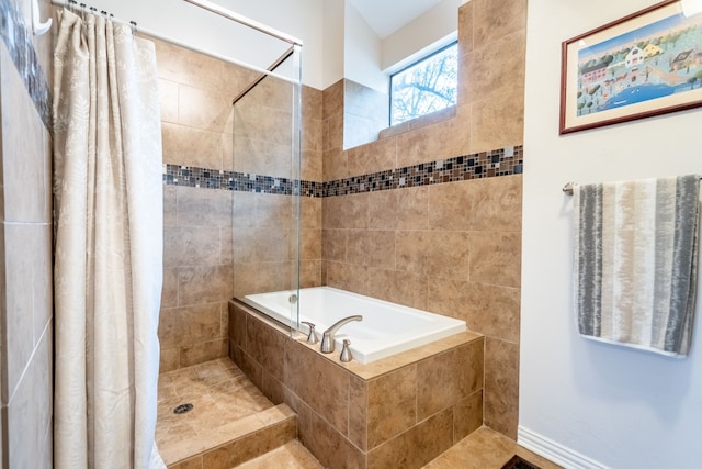 bathroom with a relaxing tiled tub and a tile shower