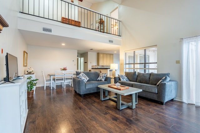 living room featuring dark wood finished floors, visible vents, and a high ceiling