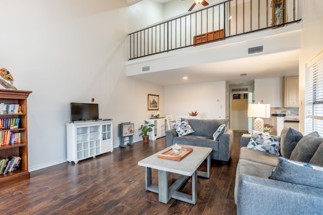 living room with baseboards, visible vents, a high ceiling, and wood finished floors