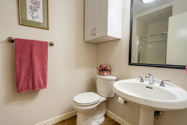 full bath featuring a shower with door, baseboards, toilet, and a sink