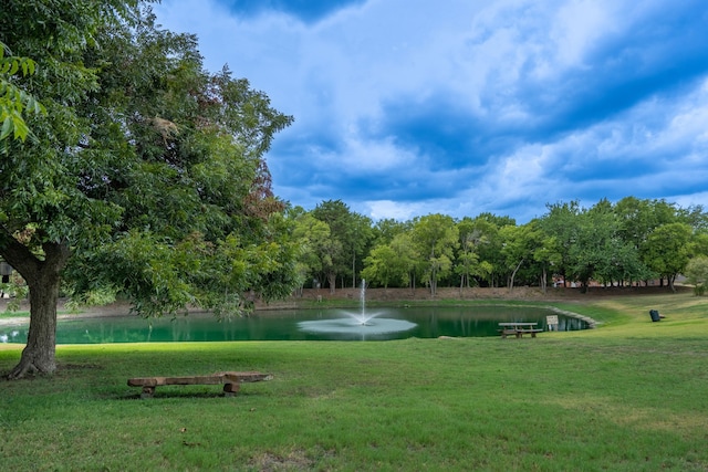 view of home's community with a water view and a yard