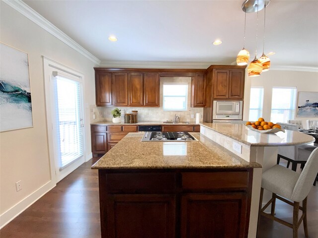 1217 Kings Hwy, Dallas, TX 75208 - kitchen featuring ornamental molding, stainless steel gas cooktop, a kitchen island, white microwave, and a kitchen bar