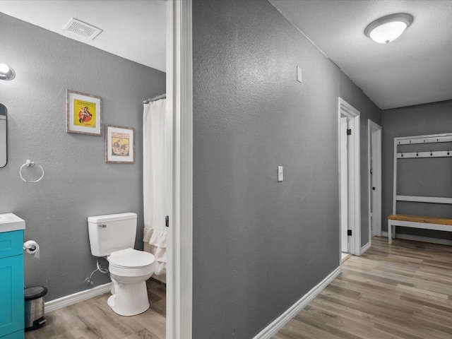 1306 Hulme St, Bowie, TX 76230 - full bathroom with visible vents, baseboards, toilet, wood finished floors, and vanity