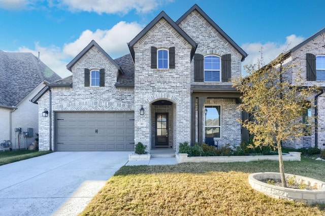 french country home with driveway, brick siding, and a front yard