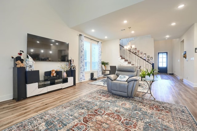 living room with baseboards, stairs, wood finished floors, and recessed lighting