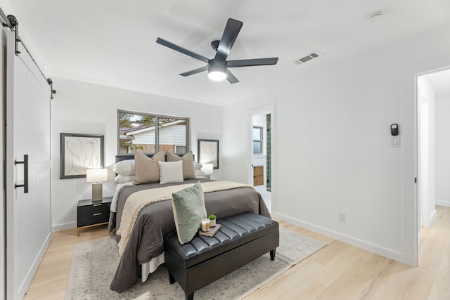 9056 Berkshire Dr, Frisco, TX 75033 - bedroom featuring a barn door, light wood-type flooring, baseboards, and ceiling fan