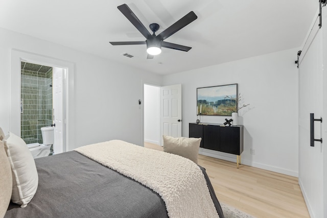 9056 Berkshire Dr, Frisco, TX 75033 - bedroom with light wood-style flooring, baseboards, a ceiling fan, connected bathroom, and a barn door