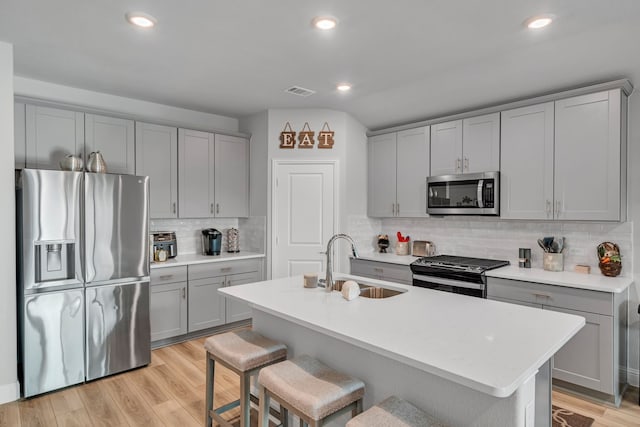 14013 Corvus Dr, Haslet, TX 76052 - kitchen featuring appliances with stainless steel finishes, gray cabinets, backsplash, light wood-style flooring, and recessed lighting