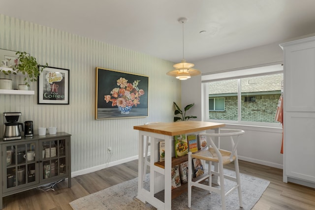 dining room with wallpapered walls, baseboards, and wood finished floors