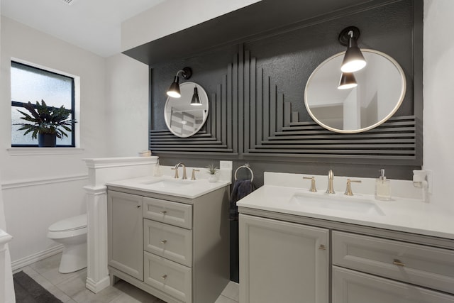bathroom featuring a sink, toilet, and two vanities