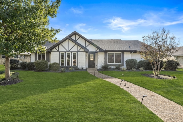tudor house with a front yard and brick siding
