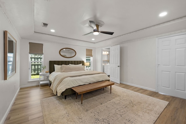 bedroom with a raised ceiling, light wood-style flooring, baseboards, visible vents, and recessed lighting