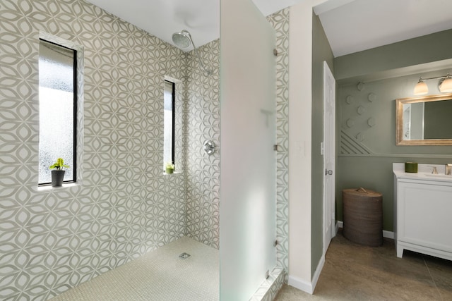 bathroom featuring baseboards, a tile shower, and vanity