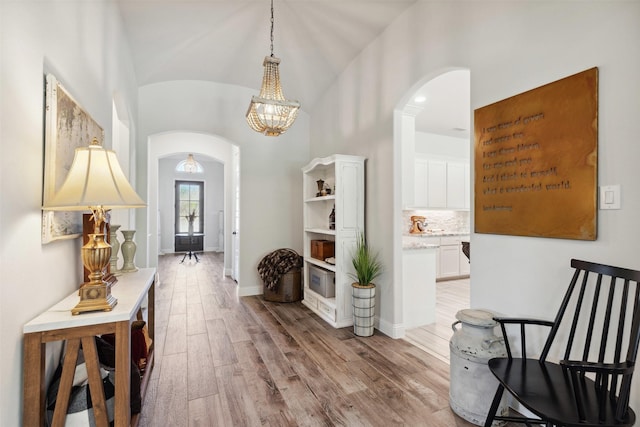 2602 Cypress Dr, Rockwall, TX 75087 - hall featuring an inviting chandelier, arched walkways, vaulted ceiling, baseboards, and light wood-style floors