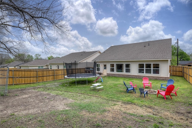 914 Edgar St, Greenville, TX 75401 - rear view of house with roof with shingles, a trampoline, an outdoor fire pit, a fenced backyard, and a lawn