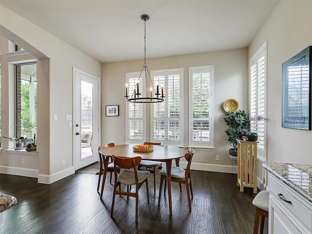 dining space with baseboards, a chandelier, and dark wood finished floors