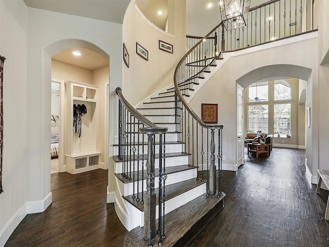 foyer entrance with arched walkways, wood finished floors, baseboards, and stairs