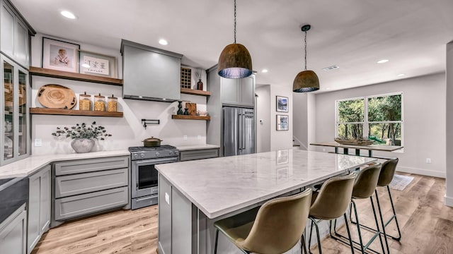 118 E Bay Dr, Bridgeport, TX 76426 - kitchen featuring light stone counters, open shelves, appliances with stainless steel finishes, range hood, and gray cabinetry