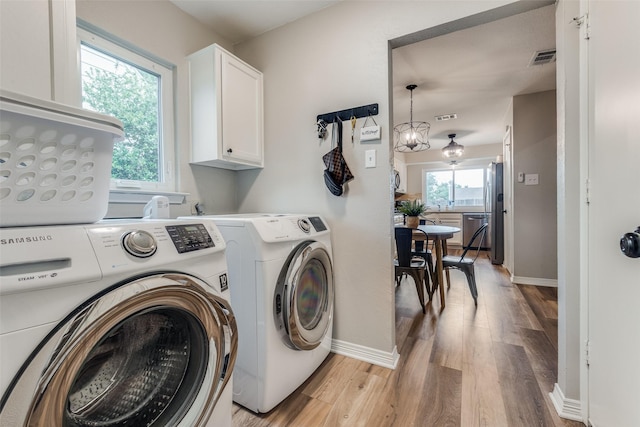 clothes washing area with cabinet space, separate washer and dryer, light wood-style floors, and a healthy amount of sunlight