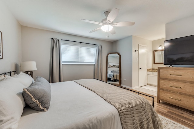 bedroom featuring connected bathroom, baseboards, light wood-type flooring, and a ceiling fan