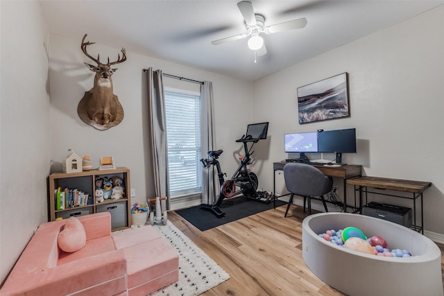 office with light wood-style floors and a ceiling fan
