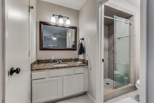 full bath featuring toilet, tile patterned floors, a ceiling fan, vanity, and a stall shower