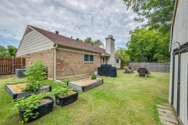 view of yard with a fenced backyard, central AC, and a vegetable garden