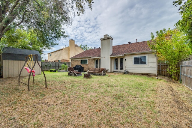 rear view of property with french doors, a fenced backyard, an outdoor structure, and a storage shed