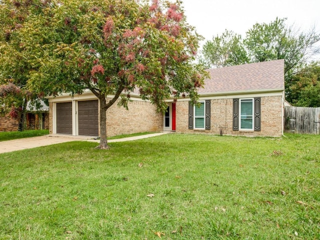 ranch-style home with roof with shingles, a front yard, fence, and concrete driveway