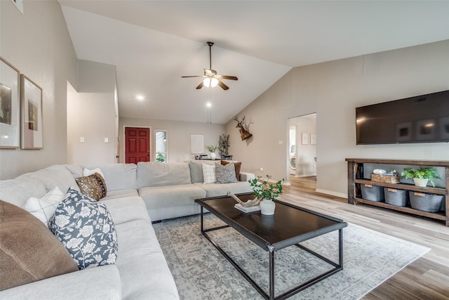 living room featuring vaulted ceiling, a ceiling fan, wood finished floors, washer / dryer, and baseboards