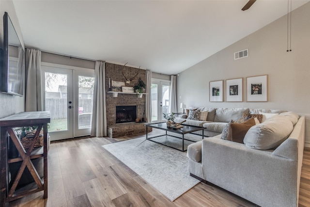 living room featuring french doors, a ceiling fan, a fireplace, wood finished floors, and visible vents