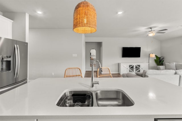 kitchen featuring stainless steel fridge with ice dispenser, light countertops, a sink, and a ceiling fan