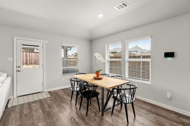 dining area with dark wood-style floors, visible vents, baseboards, and vaulted ceiling